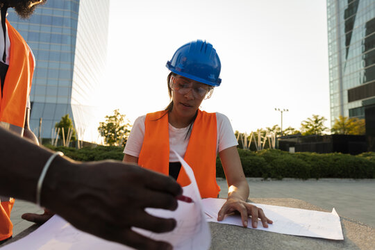 Construction engineers discussing architectural blueprints on