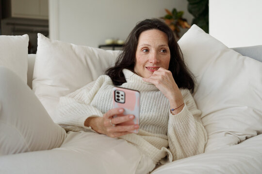 Woman Enjoying Time on Couch While Using Smartphone Indoors