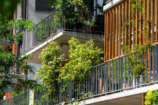 Planted balconies above a landscaped walkway in Europe, with residential greenery integrated into modern buildings and urban architecture