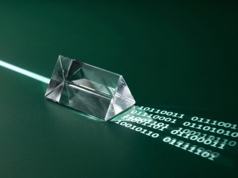 Crystal prism bending green laser beam with reflections of digital green binary matrix code numbers on dark surface.