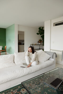 Woman Seated in Living Room With Green Wall and White Sofa