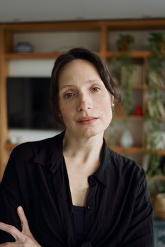 Woman in Black Shirt Standing Indoors With a Thoughtful Expression