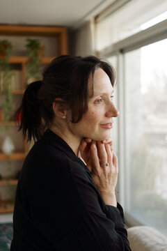 Woman Looking out the Window While Resting Her Chin on Her Hands