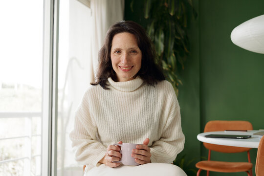 Woman Sits and Enjoys a Drink in a Bright, Modern Room
