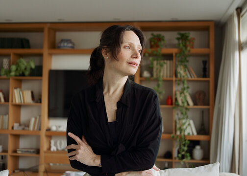 Woman Standing in Living Room Looking out the Window During Daytime