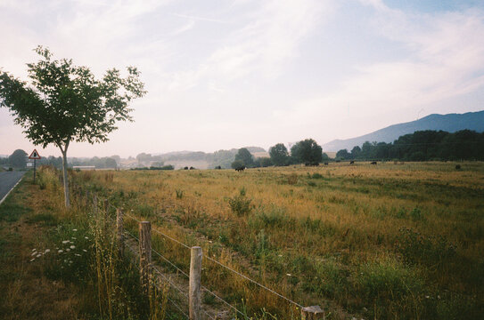 Scenic Rural Field With Wooden Fence And Mountains