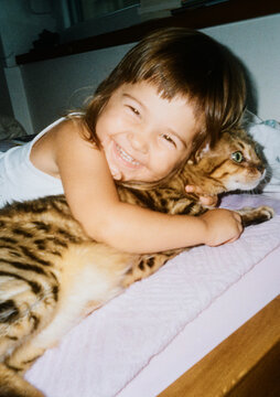 Child Smiles While Hugging a Cat