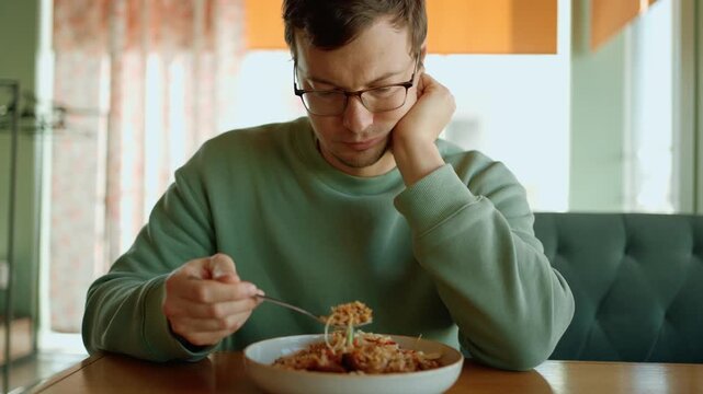 Sad lonely man with no appetite having lunch alone in a restaurant, a depressed and pensive person thinking about his problems while looking out the window with an unhappy expression