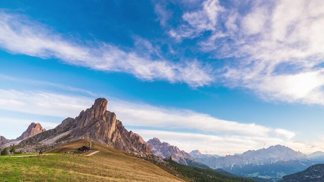 Time lapse of golden sunrise light on Ra Gusela peak at Passo Giau, Dolomites, Italy. Shadows creep across an alpine meadow under a clear sky. Serenity, passing time and freedom in the mountains