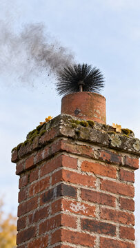 Chimney Brush Pushing Soot Out of Brick Chimney Top
