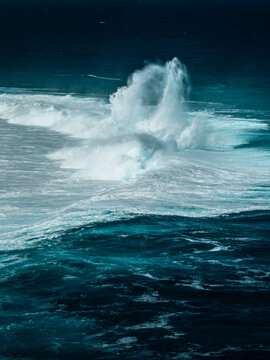 Aerial view of powerful ocean waves crashing over the coral reef with vibrant turquoise water and white sea foam in Aitutaki, Cook Islands.
