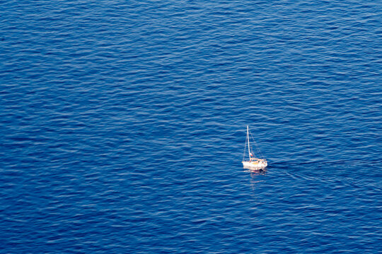 View of a small white sailboat gliding across the deep blue Mediterranean Sea near the coast of Nice, Provence-Alpes-Cote d'Azur, France.