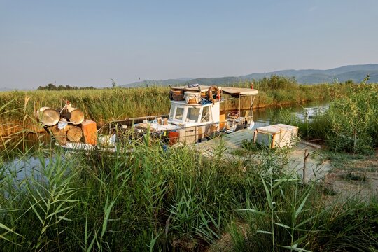 View of a small fishing boat docked in the reeds of the Azmak River with fishing gear and crates on board in Akyaka, Mugla, Turkey.