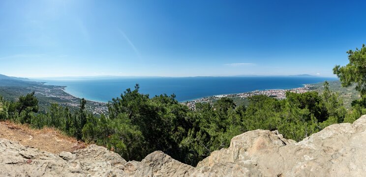 View of the coastal landscape and town nestled among lush green trees overlooking the Aegean Sea from Zeus Altar, Adatepe, Canakkale, Turkey.