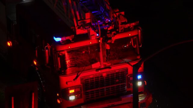 Fire emergency truck on accident scene at night. First responders fire vehicle rescue at city street. Fire truck with flashing emergency lights at night.