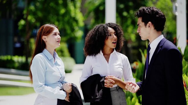 Three young professionals swap ideas in the open air with coffee, the camera close enough to catch every expression as the discussion moves around the little circle