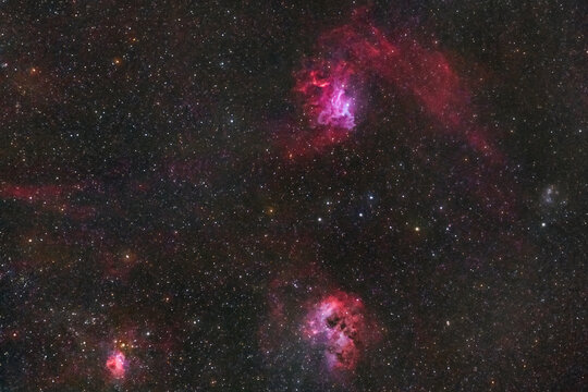View of the vibrant Flaming Star and Tadpole Nebulae glowing in the deep space of the night sky over Poland.