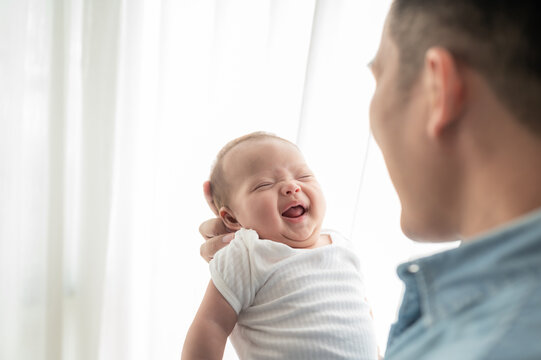 Happy Newborn Baby Being Held by Loving Father at Home