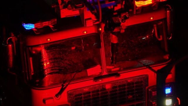 Fire truck first responders with flashing emergency lights at night fire accident scene. Firetruck with glowing lights responding and arrive to emergency call alert. Emergency siren flashing.