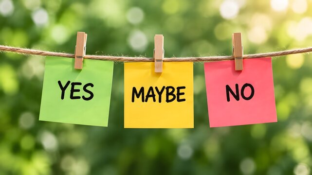 Colorful sticky notes attached with wooden clothespins to a garden twine rope outdoors, featuring handwritten words yes, maybe, and no representing decision making and uncertainty choices.