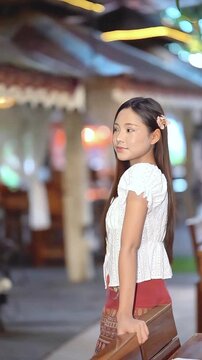Slow motion of a beautiful Asian woman in traditional Thai attire posing gracefully outdoors.