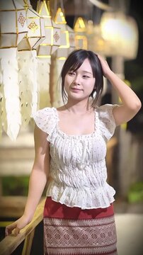 Slow motion of a beautiful Asian woman in traditional Thai attire posing gracefully outdoors.