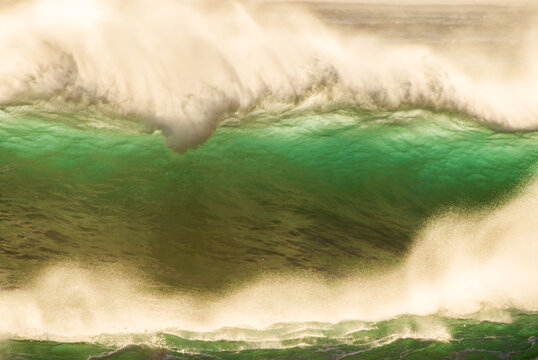 View of a powerful, large ocean wave breaking with deep green water and white sea spray at the North Shore in Haleiwa, Hawaii, United States.