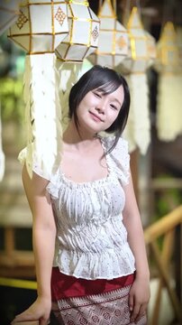 Slow motion of a beautiful Asian woman in traditional Thai attire posing gracefully outdoors.