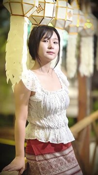 Slow motion of a beautiful Asian woman in traditional Thai attire posing gracefully outdoors.