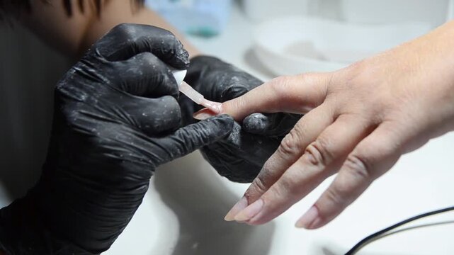 Close-up of a professional manicure procedure performed by a nail technician in a beauty salon. Fingernail care, grooming and cosmetic treatment concept.