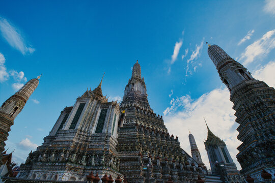 View of the ornate central prang and surrounding spires of Wat Arun temple against a clear blue sky in Bangkok, Bangkok, Thailand.