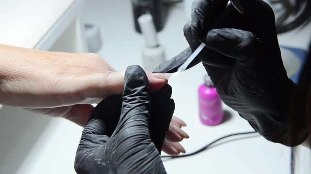 Close-up of a professional manicure procedure performed by a nail technician in a beauty salon. Fingernail care, grooming and cosmetic treatment concept.