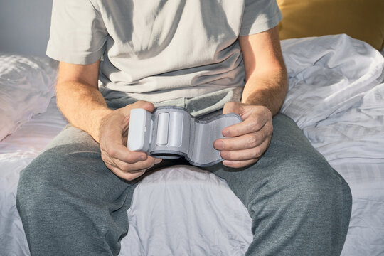 Man holding wrist blood pressure monitor, checking his health at home