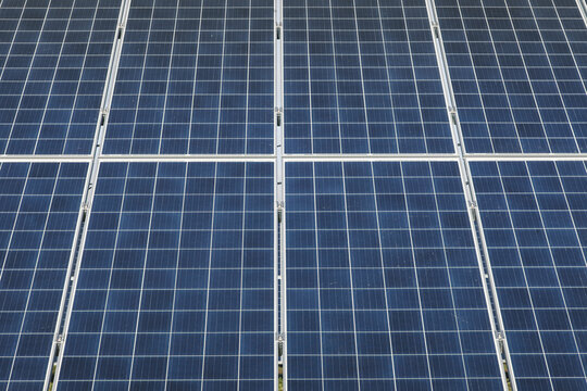 View of blue photovoltaic solar panels arranged in a grid pattern for renewable energy generation in Tartu County, Estonia.