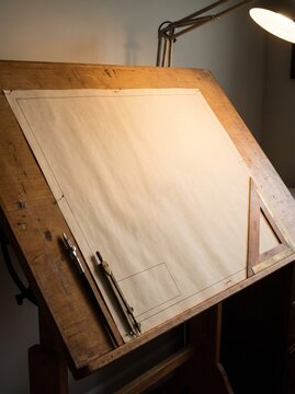 Blank Drafting Paper On Angled Wooden Drafting Table With Lamp