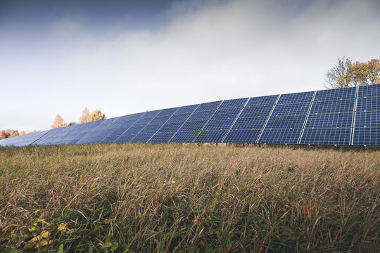 View of a large solar panel array installed in a grassy field under a cloudy sky in Otepaa, Valga County, Estonia.