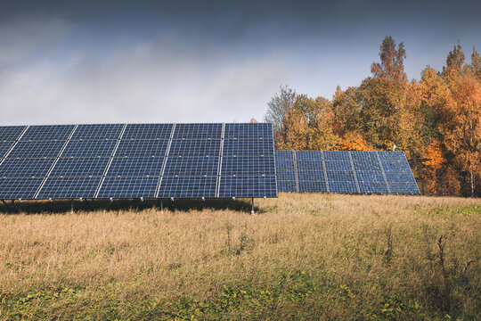 View of solar panels installed in a grassy field with autumn trees in the background under a cloudy sky in Otepaa, Valga County, Estonia.