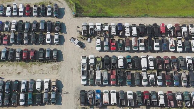 Aerial view of large car lot filled with parked vehicles. Rows of cars stretch across sandy ground. Scene shows quiet, organized storage area. Useful for automotive, logistics