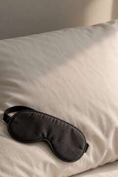 Plain fabric sleep mask resting on a soft pillow