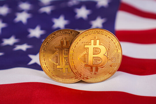 Extreme close-up of two physical gold Bitcoin coins on the United States flag.