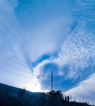 View of a dramatic blue sky with textured clouds and power lines stretching across the horizon in Jos North, Plateau, Nigeria.