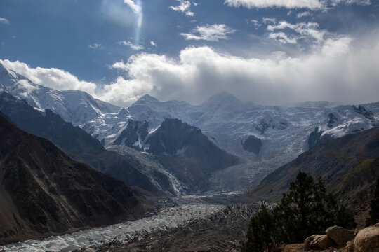 View of Nanga Parbat with its massive snow-covered peaks, glaciers, and rocky slopes under a blue sky with clouds in Fairy Meadow, Gilgit, Pakistan.