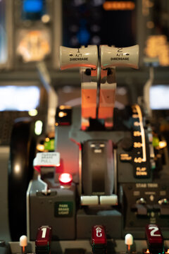 View of the throttle quadrant and flight controls inside a Boeing 737-800 cockpit with illuminated buttons and levers in Langenhagen, Niedersachsen, Germany.
