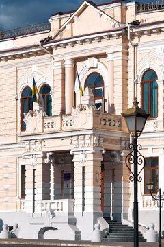 Elegant historic building with ornate facade, arched windows, manicured gardens, and decorative street lamps