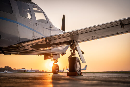 View of a light aircraft parked on the tarmac at Hannover Airport during sunset with warm golden light in Langenhagen, Niedersachsen, Germany.