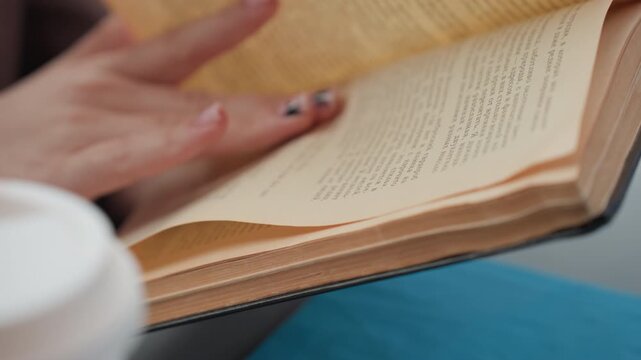 Close up view of hands turning book pages with pink nail polish and star design. Visible text on paper supports educational or literary context. Soft lighting creates calm focused atmosphere