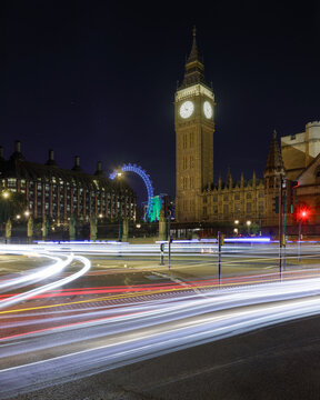 View of Big Ben illuminated at night with light trails from passing traffic on the streets of London, England, United Kingdom.