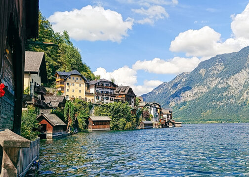 View of the historic village of Hallstatt with traditional alpine houses nestled along the lake shore under a bright blue sky in Hallstatt, Upper Austria, Austria.