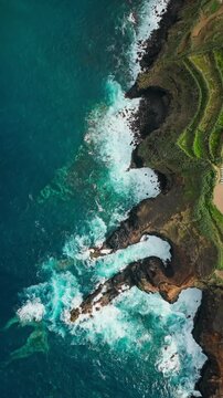 Top down aerial view of Atlantic waves around volcanic headland and dark coastal rocks. Ocean swell, breaking waves and white sea foam
