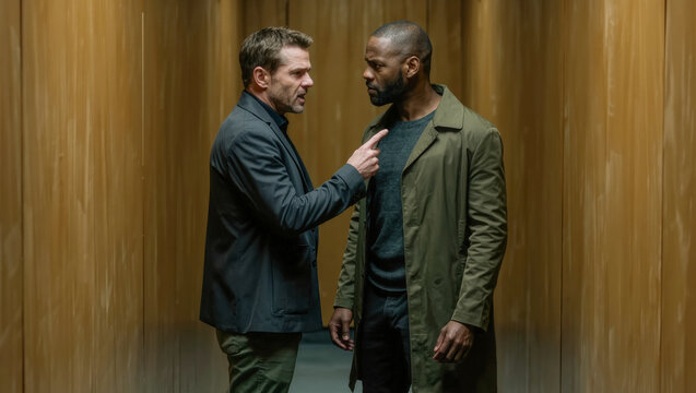 Two men in heated confrontation against wooden paneled wall
